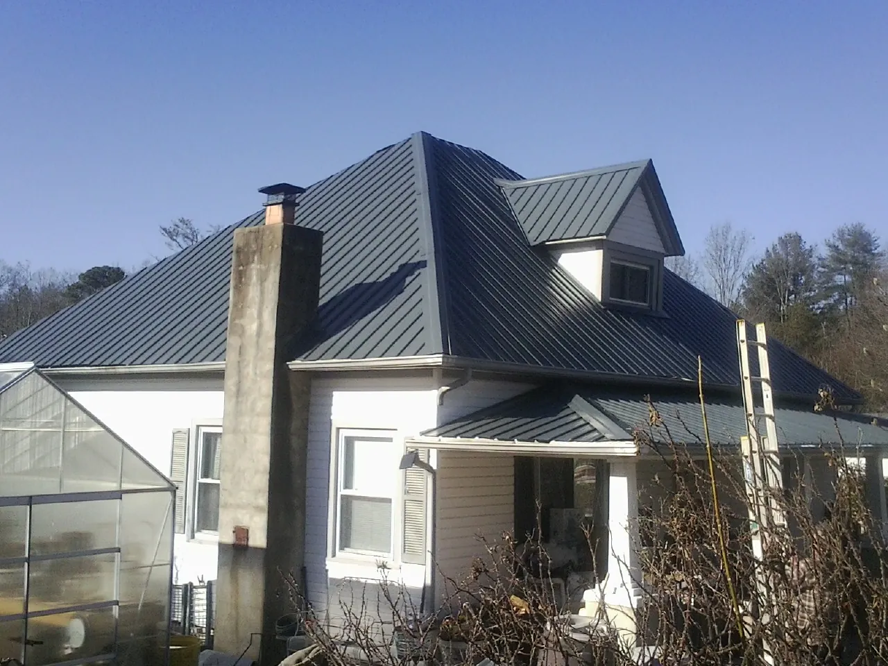 Dark blue standing seam metal roof on a white farmhouse with dormer — Slate & Tile Roof Repair by Roofing Brothers in Franklin Lakes