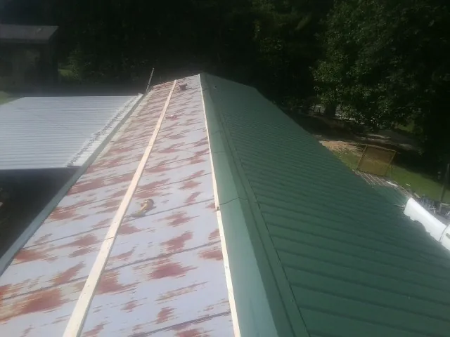 Old rusted panels beside newly installed green metal roofing — Wind Damage Roof Repair by Roofing Brothers in Franklin Lakes