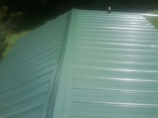 New green metal panels meeting at the ridge of a roof — Flat Roof Repair work by our crew in Franklin Lakes