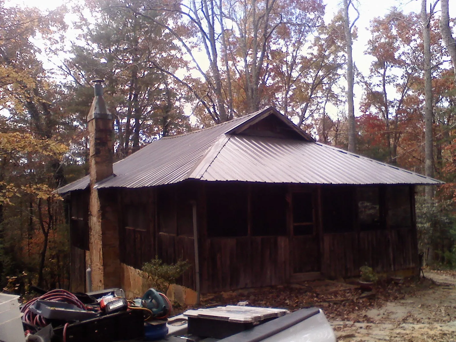 Brown metal hip roof on an old cabin with a stone chimney in Franklin Lakes