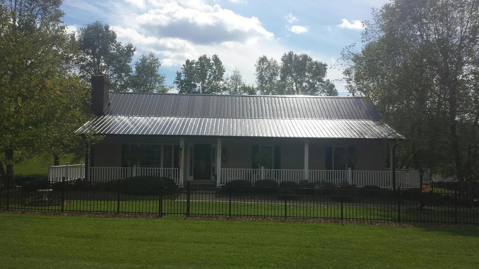 Gray metal roof on a brick ranch with a full width front porch — Gutter Guard Installation work by our crew in Franklin Lakes