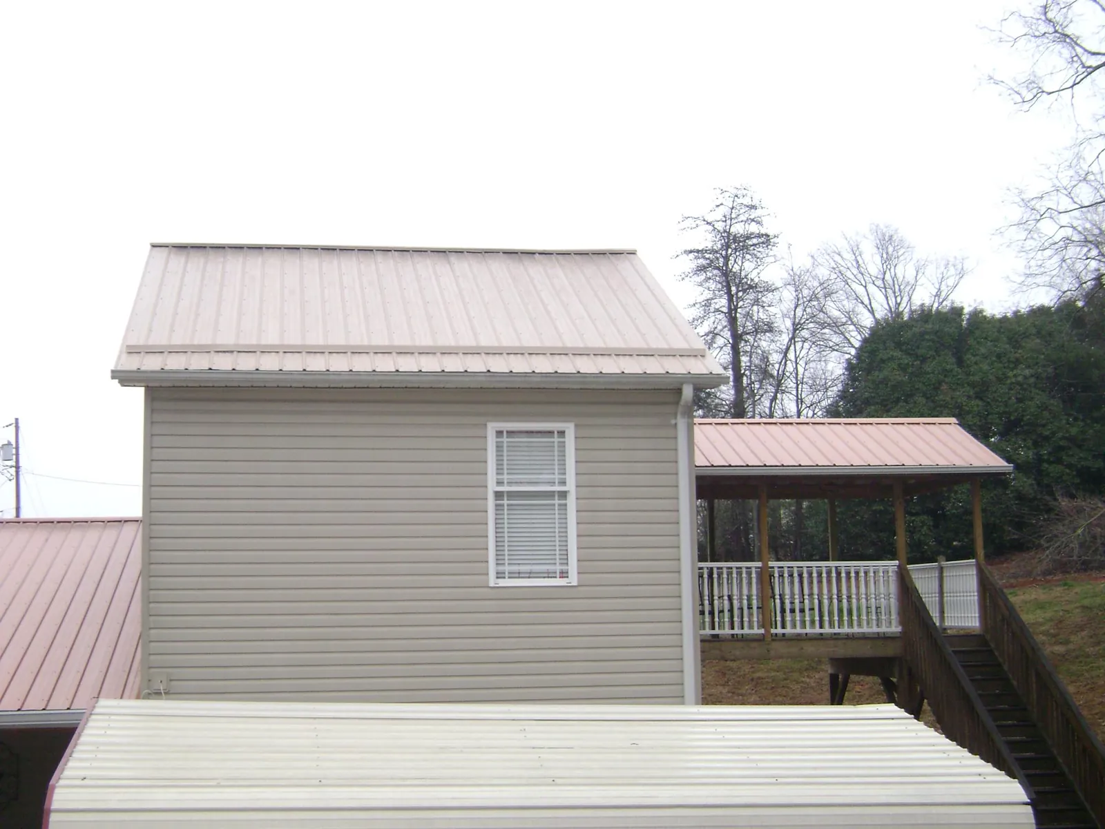 Tan metal roofs on a two story addition and attached porch, from a Roof Replacement job in Franklin Lakes
