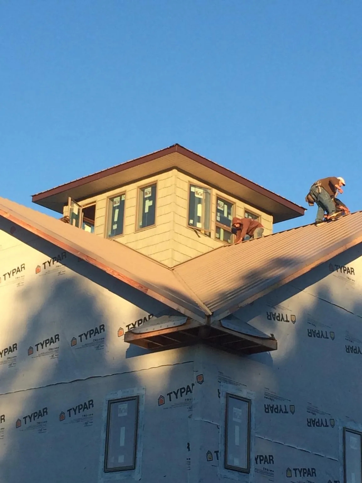Roofers working around a rooftop cupola on a new metal roof at sunset — Roof Waterproofing in Franklin Lakes by Roofing Brothers